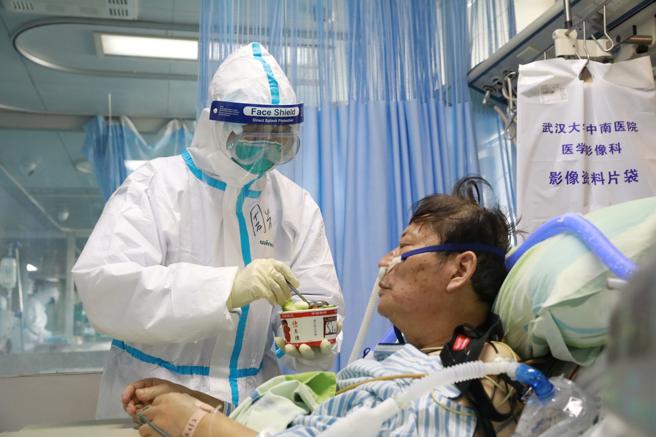 Una enfermera con traje protector atiende a un enfermo de coronavirus en un hospital de Wuhan