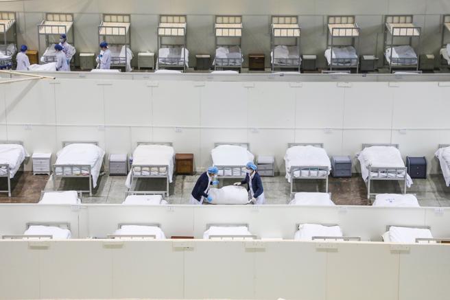 Personal hospitalaria preparan camas para enfermos de coronavirus en un centro de convenciones de Wuhan
